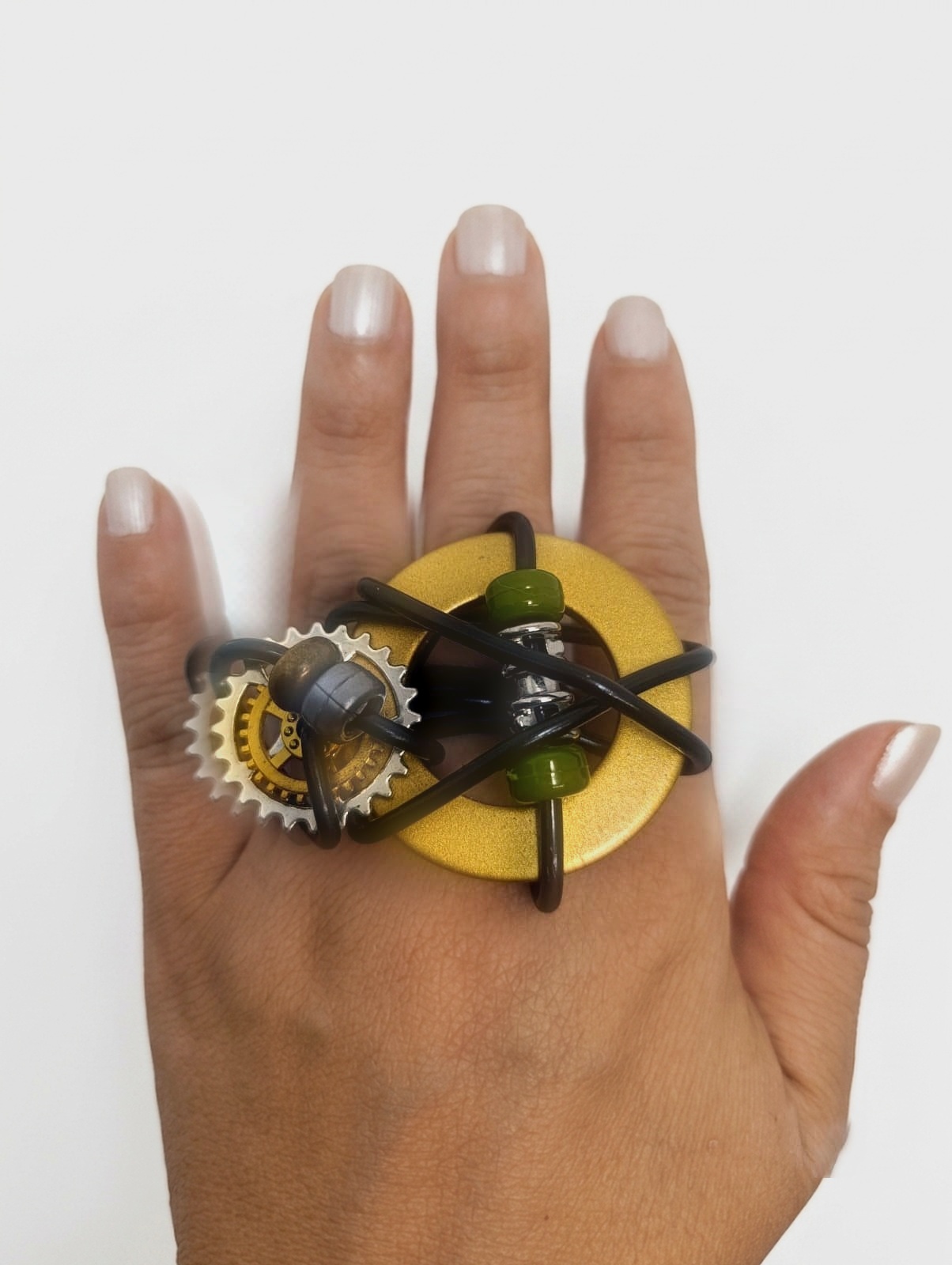 Anillo Vórtice grande sobre engranaje dorado en la mano